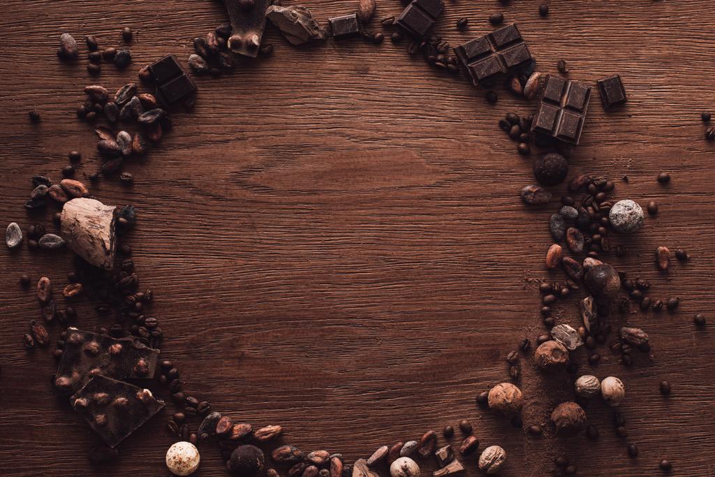 κάτοψη του κύκλου φιαγμένου από διάφορους τύπους κομμάτια σοκολάτας, Τρουφάκια, κόκκοι καφέ και κακάο στο ξύλινο τραπέζι  - Φωτογραφία, εικόνα