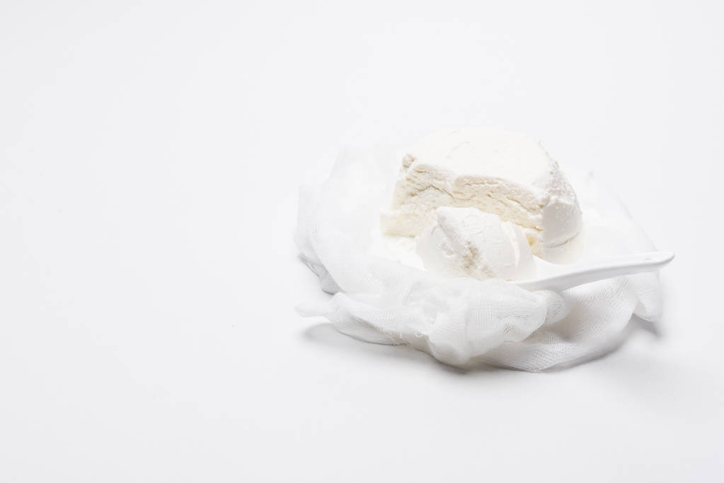 σπιτικό τυρί cottage σε cheesecloth με κουτάλι σε λευκή επιφάνεια - Φωτογραφία, εικόνα
