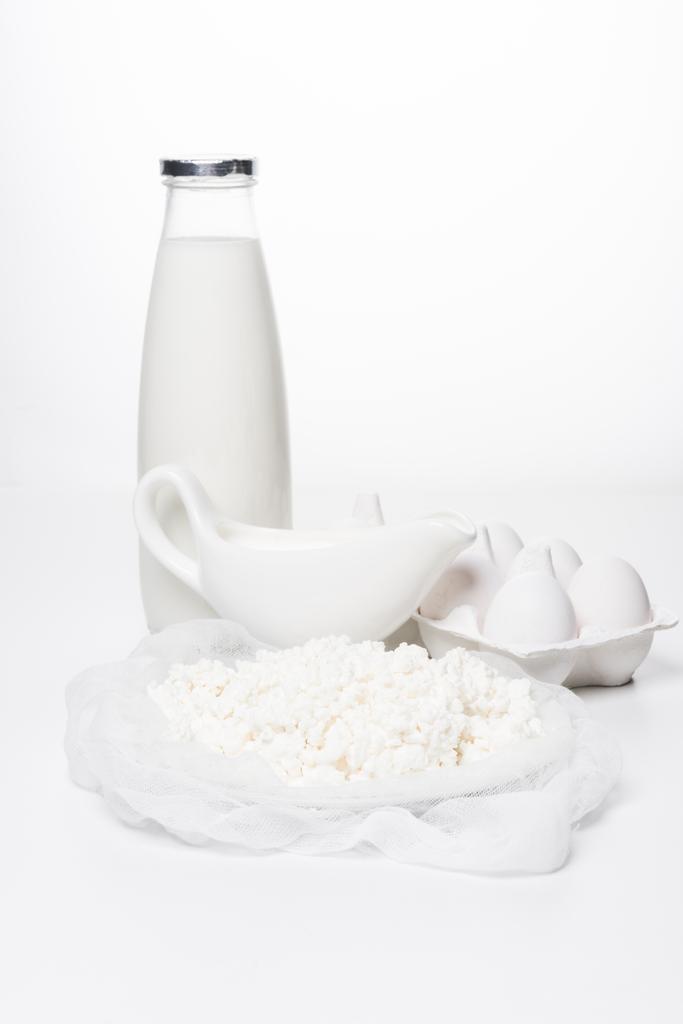 primo piano di latte, fiocchi di latte fatti in casa e uova in cartone su superficie bianca
 - Foto, immagini