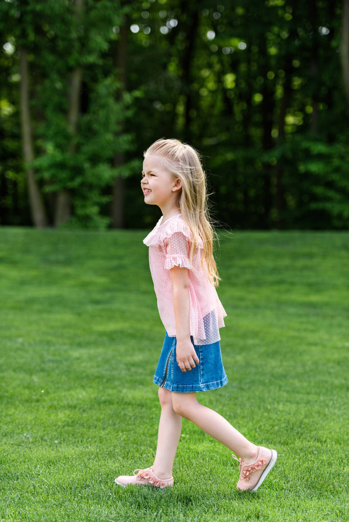widok boczny urocze małe dziecko, chodzenie na trawie w parku - Zdjęcie, obraz