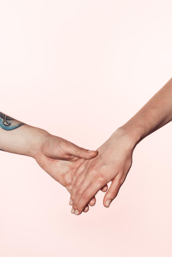 Μερική άποψη του τατουάζ άνδρας και γυναίκα, κρατώντας τα χέρια που απομονώνονται σε ροζ φόντο  - Φωτογραφία, εικόνα