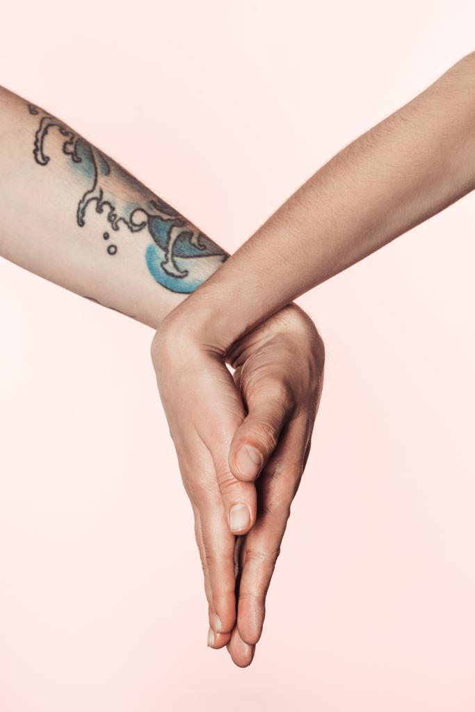 vue partielle de l'homme tatoué et de l'homme tenant les paumes ensemble isolé sur fond rose
  - Photo, image