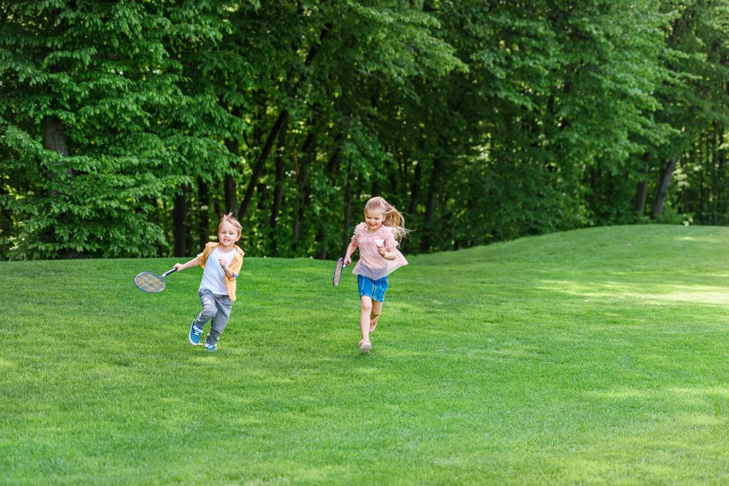 simpatici bambini con racchette da badminton che corrono insieme nel parco
  - Foto, immagini