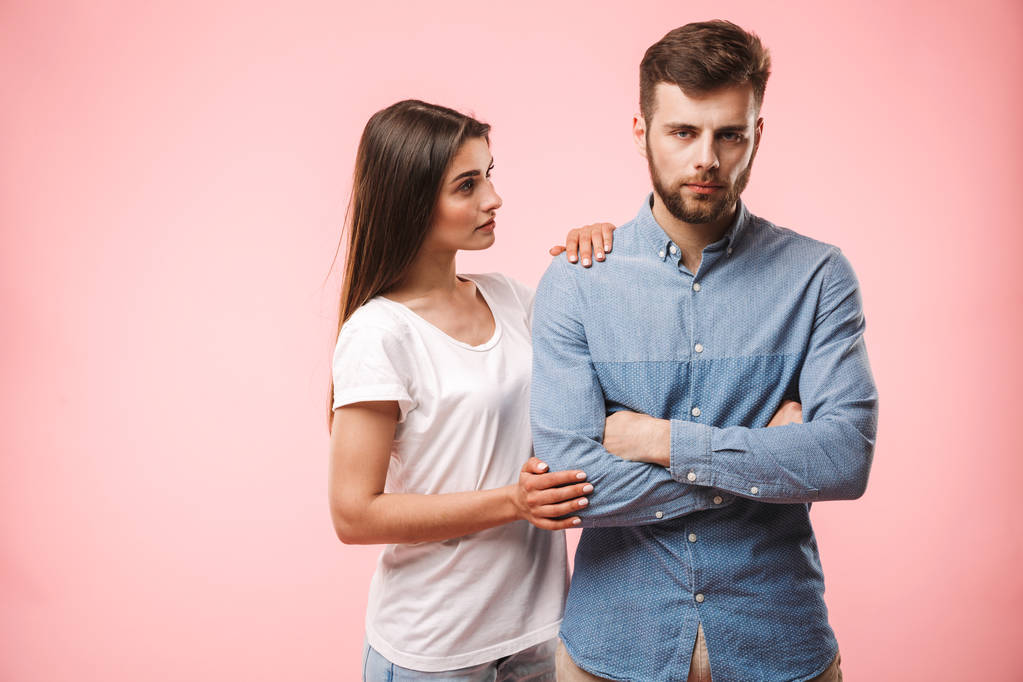Portrait of a frustrated young couple having an argument isolated over pink background - Photo, Image