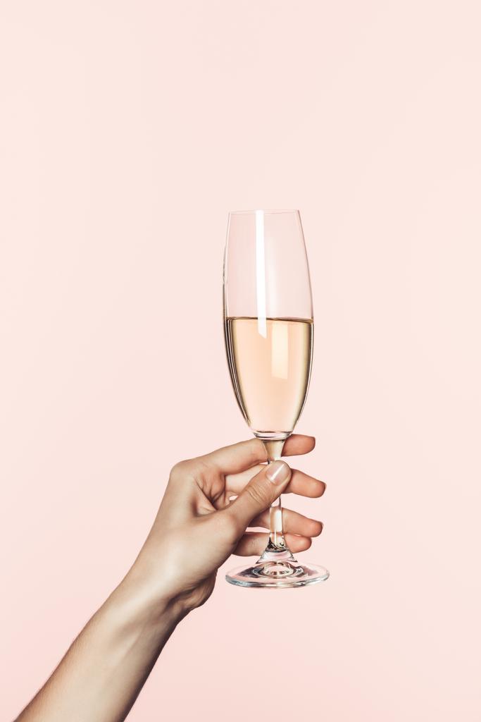 ピンクの背景に分離されたシャンパン グラスを保持している女性の部分的なビュー  - 写真・画像