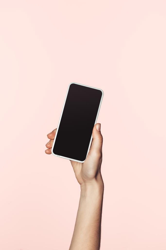 przycięte zdjęcie kobiety, trzymając smartfon z pustego ekranu na białym tle na różowym tle  - Zdjęcie, obraz