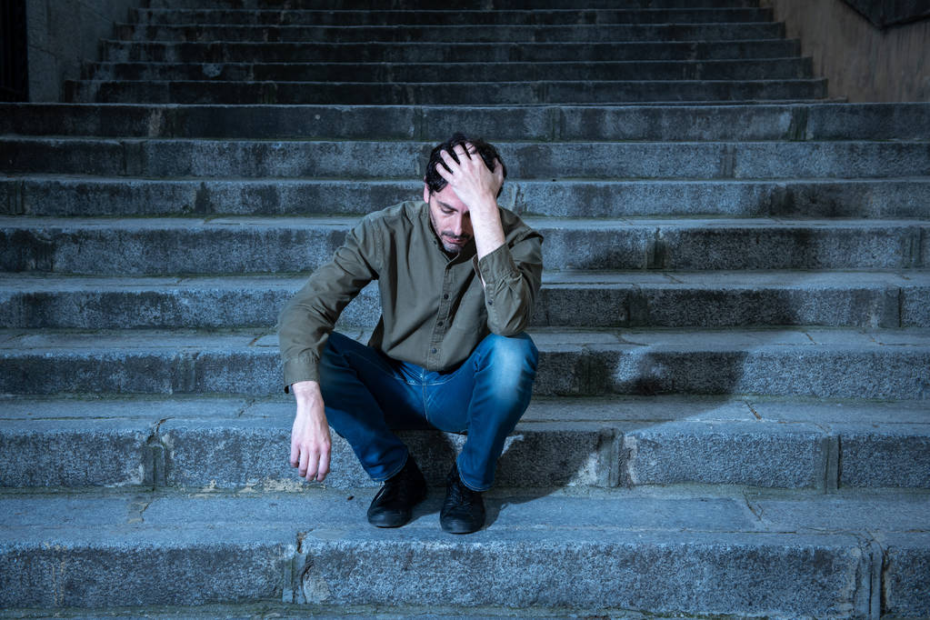 latin man stressed from work sitting on steps outside feeling anxiety in adult cause of depression and problem in living that makes you feel lonely, sad and worried in mental health concept - Photo, Image