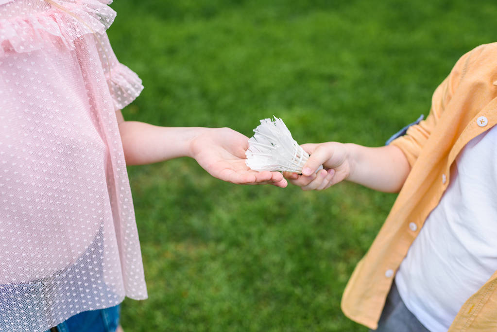 cropped shot of little kids holding shuttlecock in park - Photo, Image