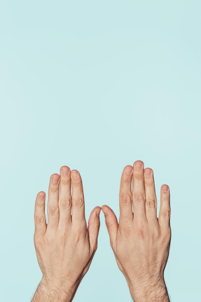 abgeschnittenes Bild männlicher Hände isoliert auf blauem Hintergrund  - Foto, Bild