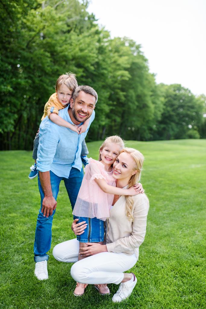 heureux famille étreignant et souriant à la caméra tout en passant du temps ensemble dans le parc
  - Photo, image