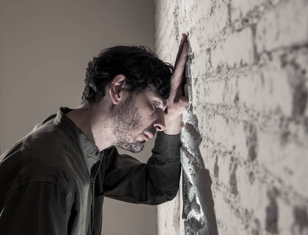 депресивний чоловік спирається на білу стіну в темній кімнаті вдома, відчуває себе сумно, втомився і стурбований концепцією депресії психічного здоров'я
. - Фото, зображення