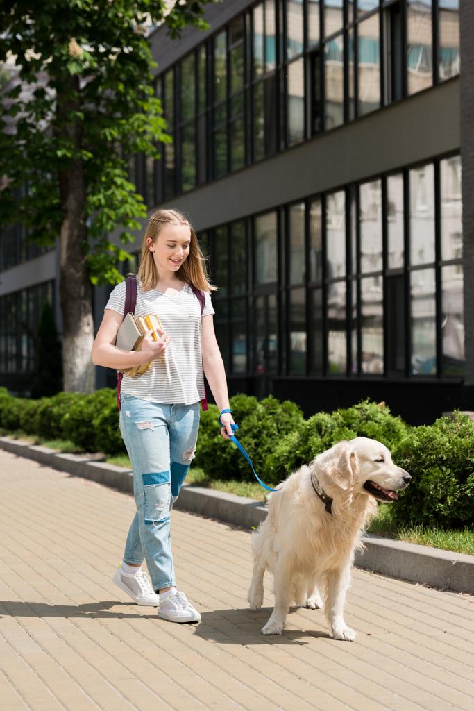Teen student girl with books walking her dog - Foto, Bild