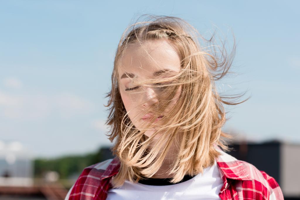 beautiful teen girl with hair waving on wind in front of blue sky - Photo, Image