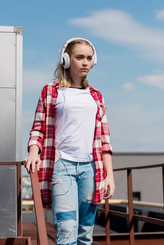 赤い格子縞のシャツと青い空の前にヘッドフォンで美しい十代の少女 - 写真・画像