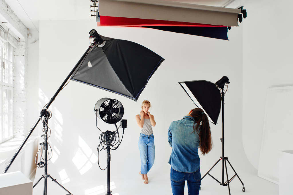 Girl photographer photographing the model in studio - Photo, Image