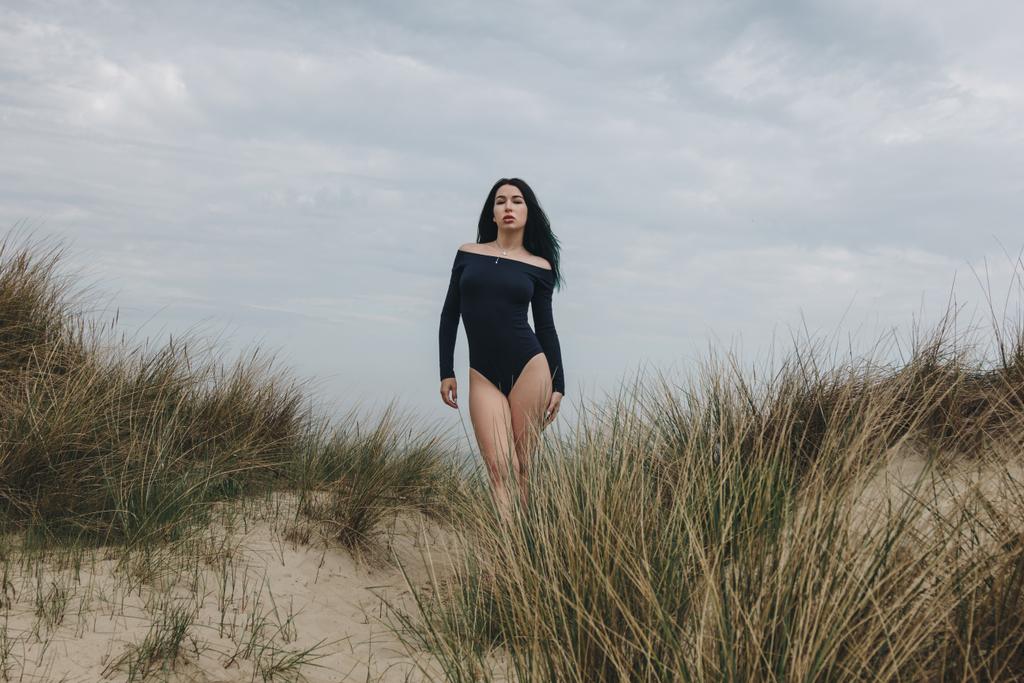 attraente giovane donna in body nero su dune di sabbia sotto cielo nuvoloso
 - Foto, immagini
