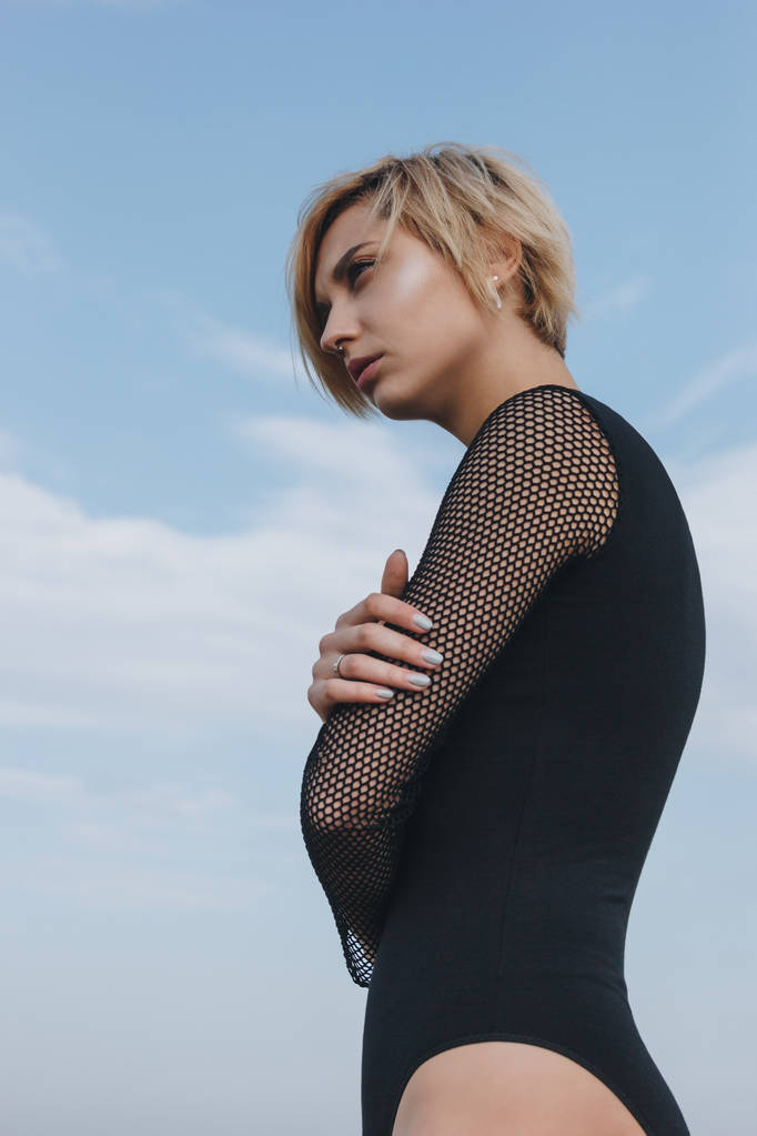 sensual young woman in black bodysuit in front of cloudy sky - Photo, Image