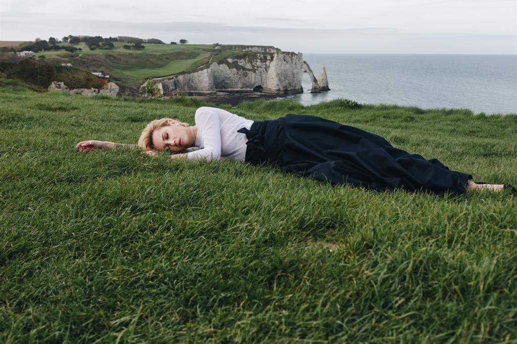привлекательная девушка лежит на зеленой траве на скале, Этрета, Нормандия, Франция
 - Фото, изображение