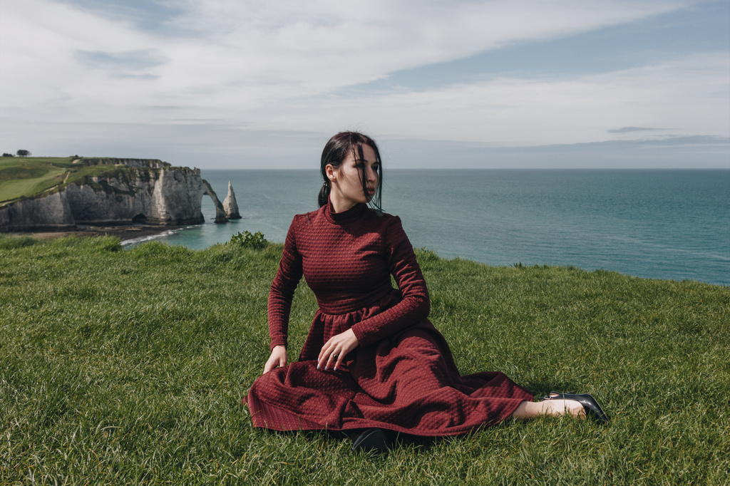 модная девушка, сидящая на зеленой скале у моря, Этреб, Нормандия, Франция
 - Фото, изображение