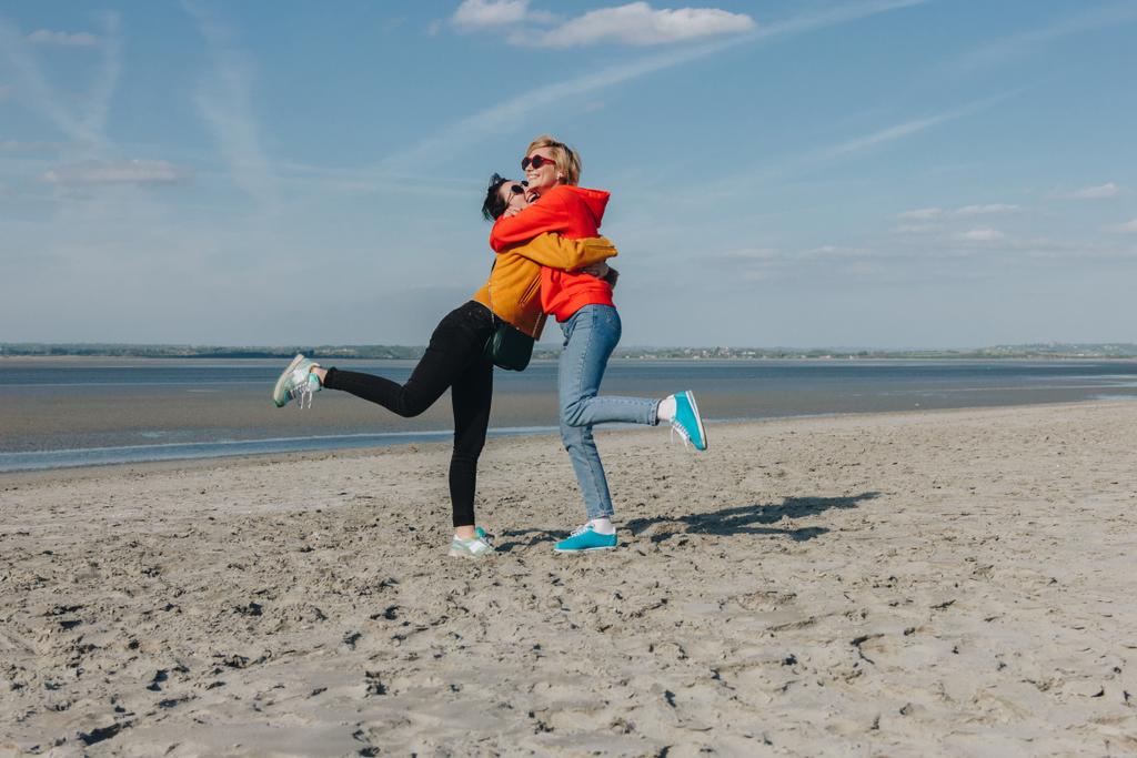 Happy vrienden knuffelen op zandstrand, mount Saint michaels, Normandië, Frankrijk - Foto, afbeelding