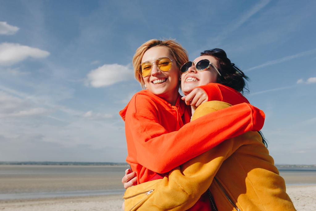 sorridente amigos do sexo feminino abraçando na praia de areia, Monte Saint michaels, Normandia, França
 - Foto, Imagem
