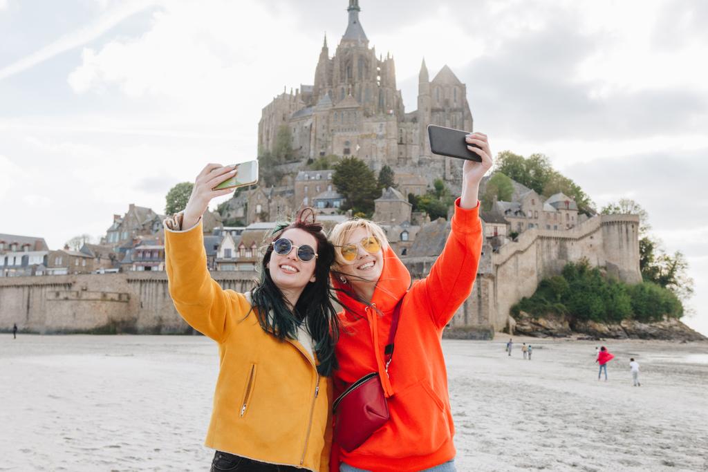 usmívající se turisté při selfie na smartphone poblíž Saint michaels mount, Normandie, Francie - Fotografie, Obrázek