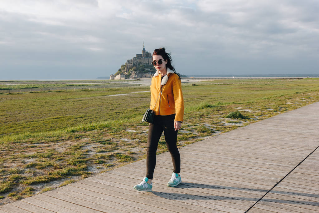 full length view of beautiful girl in sunglasses walking near mont saint michel, france - Photo, Image
