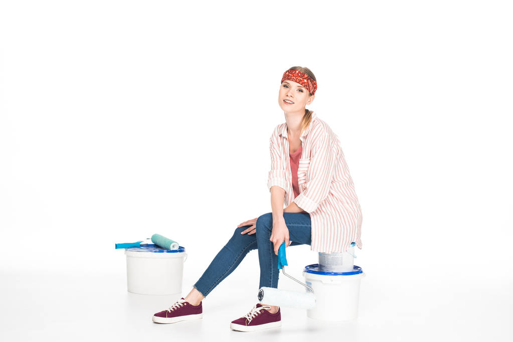 mulher na cabeça sentado com rolo de pintura em latas de tinta isoladas no fundo branco
  - Foto, Imagem