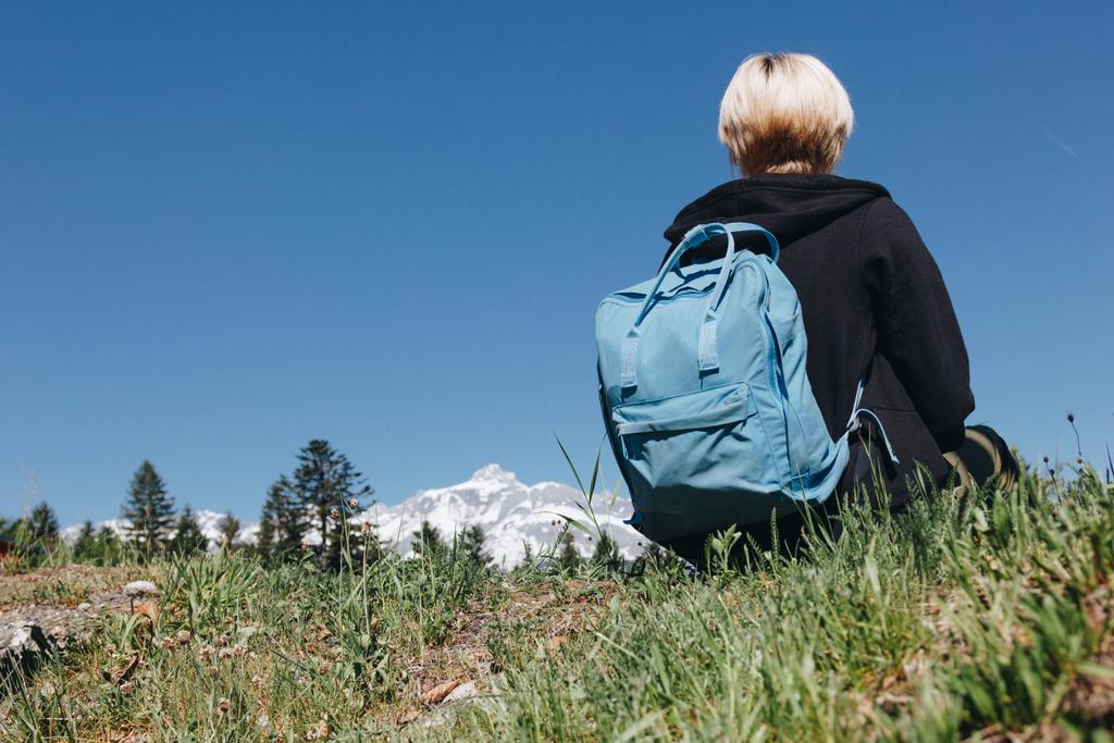вид ззаду молода жінка мандрівник з рюкзаком відпочиває на траві в горах, Монблан, Альпи
 - Фото, зображення