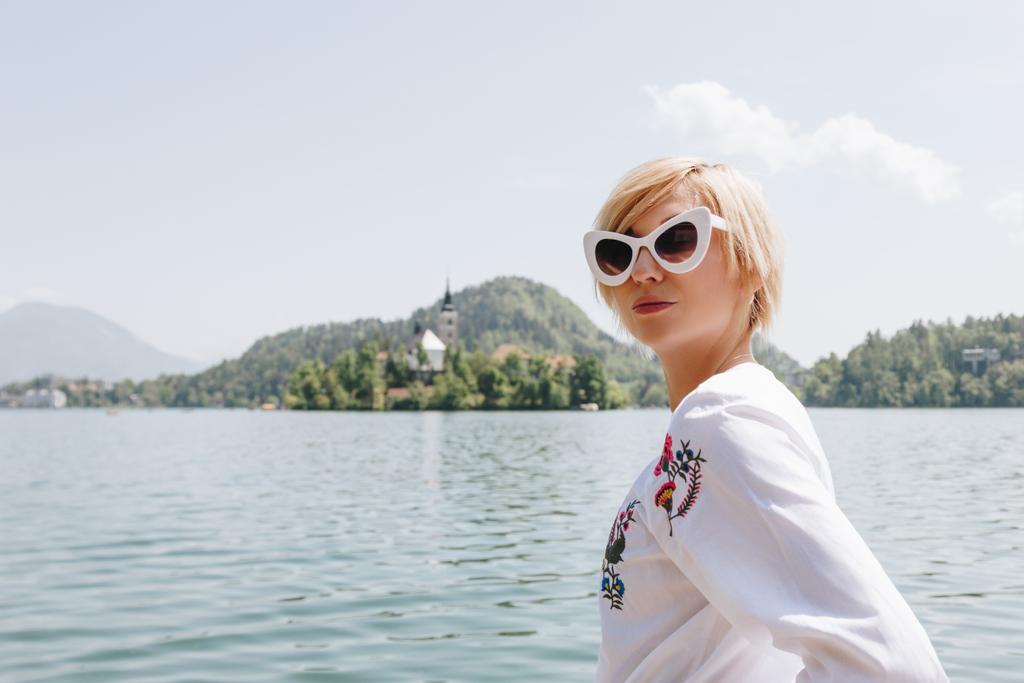 piękna młoda kobieta w okulary, stojący w pobliżu malowniczego jeziora w górach, bled, Słowenia - Zdjęcie, obraz