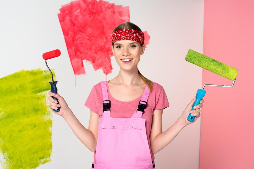 Lachende vrouw werken algemene houden verf rollers voor geschilderde muur  - Foto, afbeelding