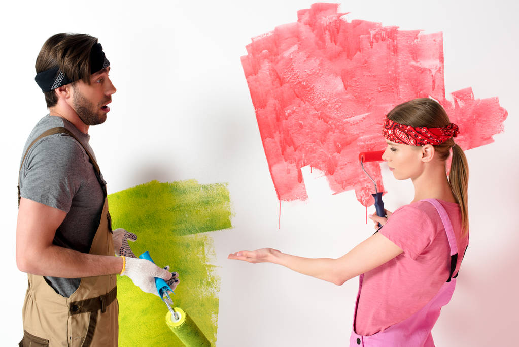 young woman pointing by hand on painted wall to boyfriend while he doing shrug gesture  - Photo, Image