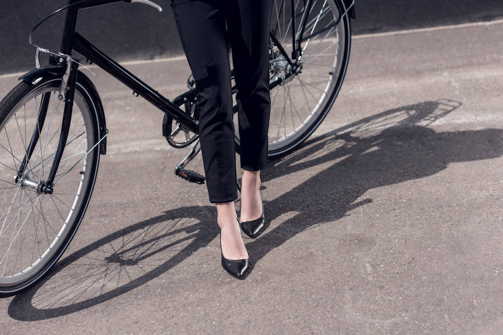 обрізаний знімок бізнес-леді в костюмі і високі підбори, що стоять біля ретро-велосипеда на вулиці
 - Фото, зображення