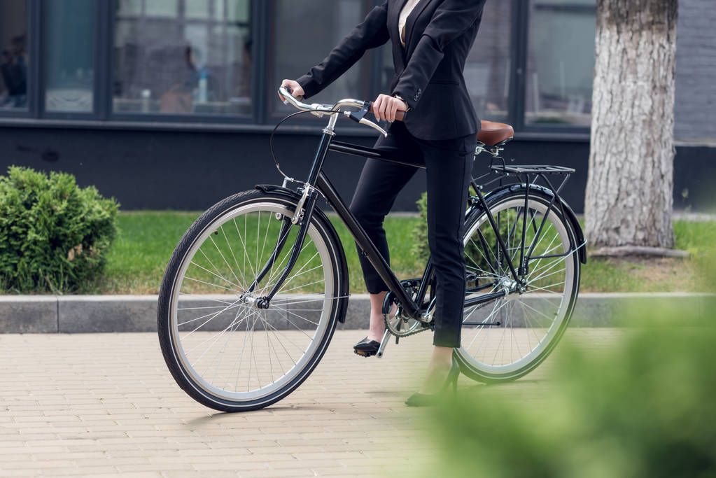 ritagliato colpo di donna d'affari in abito con bicicletta retrò sulla strada
 - Foto, immagini