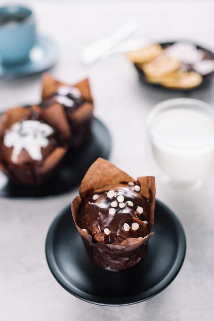 Magdalenas de chocolate dulce con vaso de leche en la mesa
 - Foto, imagen
