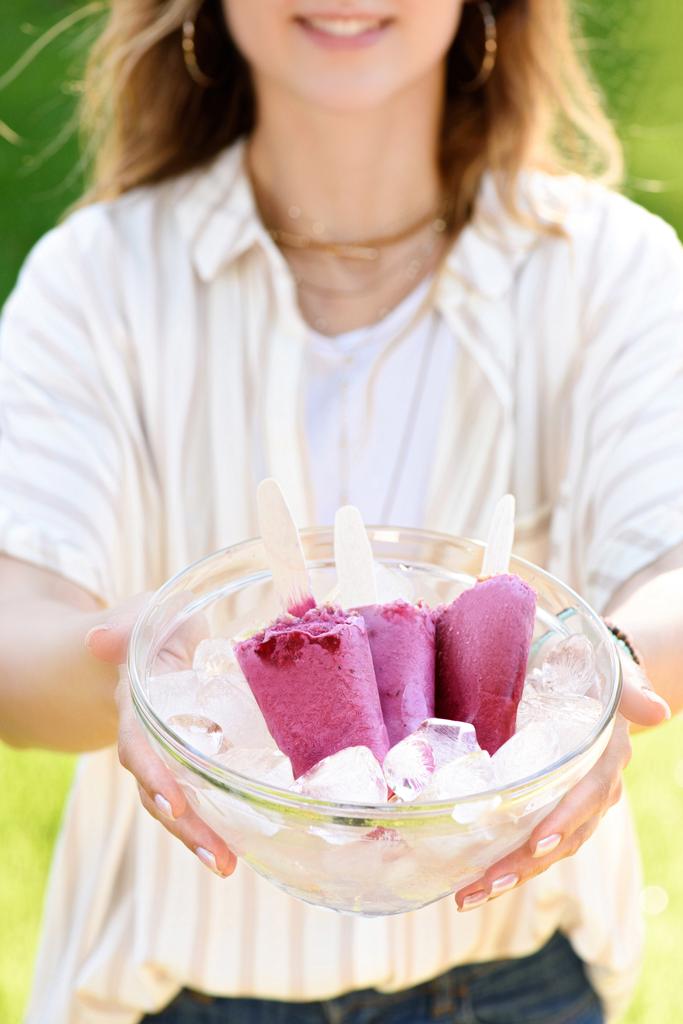 Kase berry ile çubuklu dondurmayı ve buz küpleri tutan kadın - Fotoğraf, Görsel