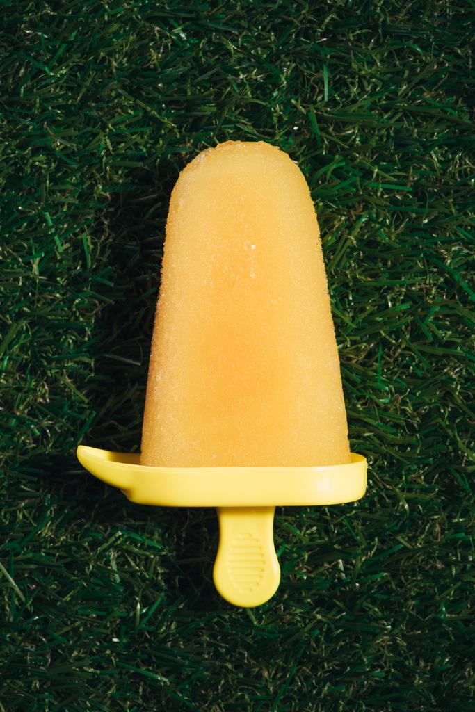 緑の草の背景に甘い黄色い果物アイス キャンデー - 写真・画像