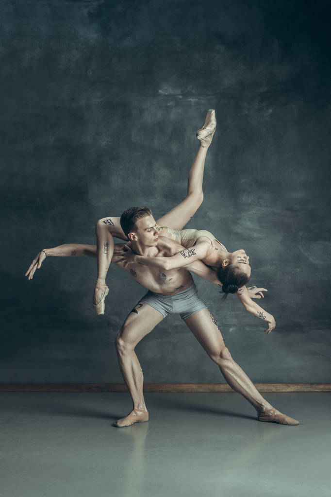 Молодые современные артисты балета позируют на фоне серой студии
 - Фото, изображение