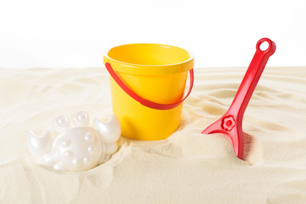 Ведро и пластиковые игрушки в песке изолированы на белом
 - Фото, изображение