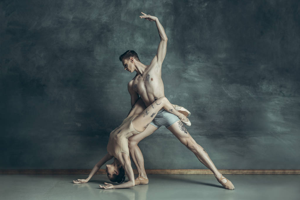 De jonge moderne balletdansers poseren op grijze studio achtergrond - Foto, afbeelding