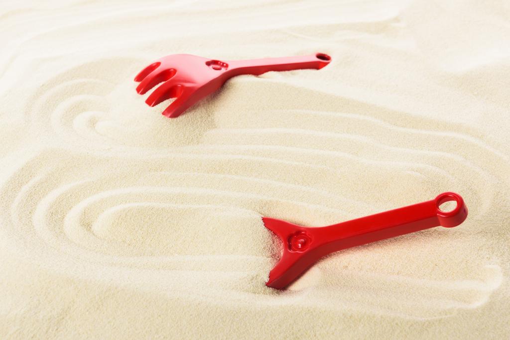 Pala de juguete y rastrillos en la playa de arena
 - Foto, imagen