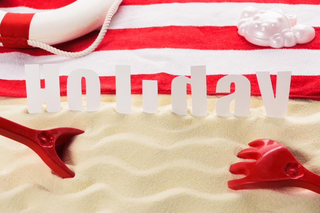 Beach toys and towel with word Holiday on sandy beach - Photo, Image