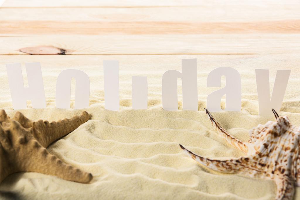 Estrella de mar con concha y la inscripción de vacaciones en la playa de arena
 - Foto, imagen