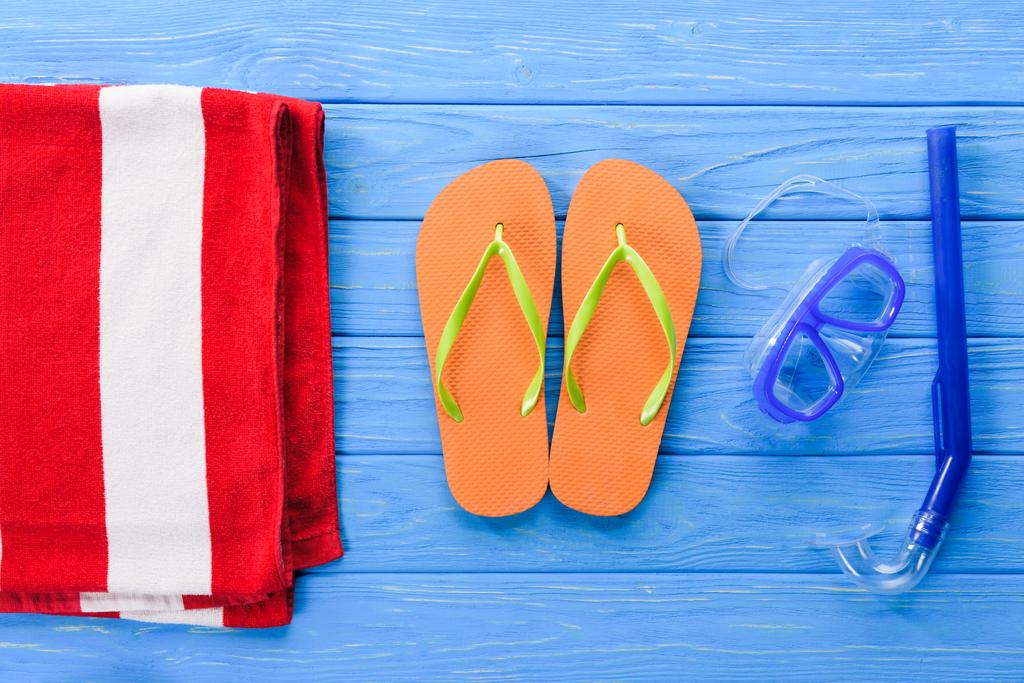 Flip flops with mask and towel on blue wooden background - Photo, Image