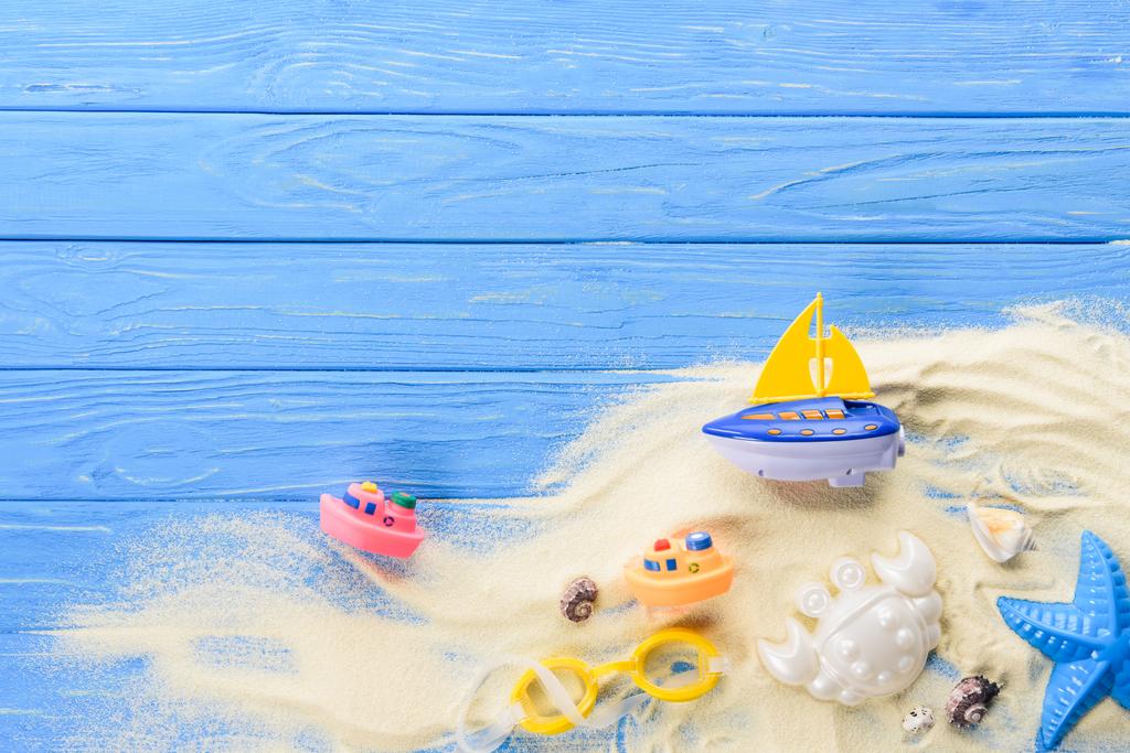 Plážové hračky v písku na modré dřevěné pozadí - Fotografie, Obrázek