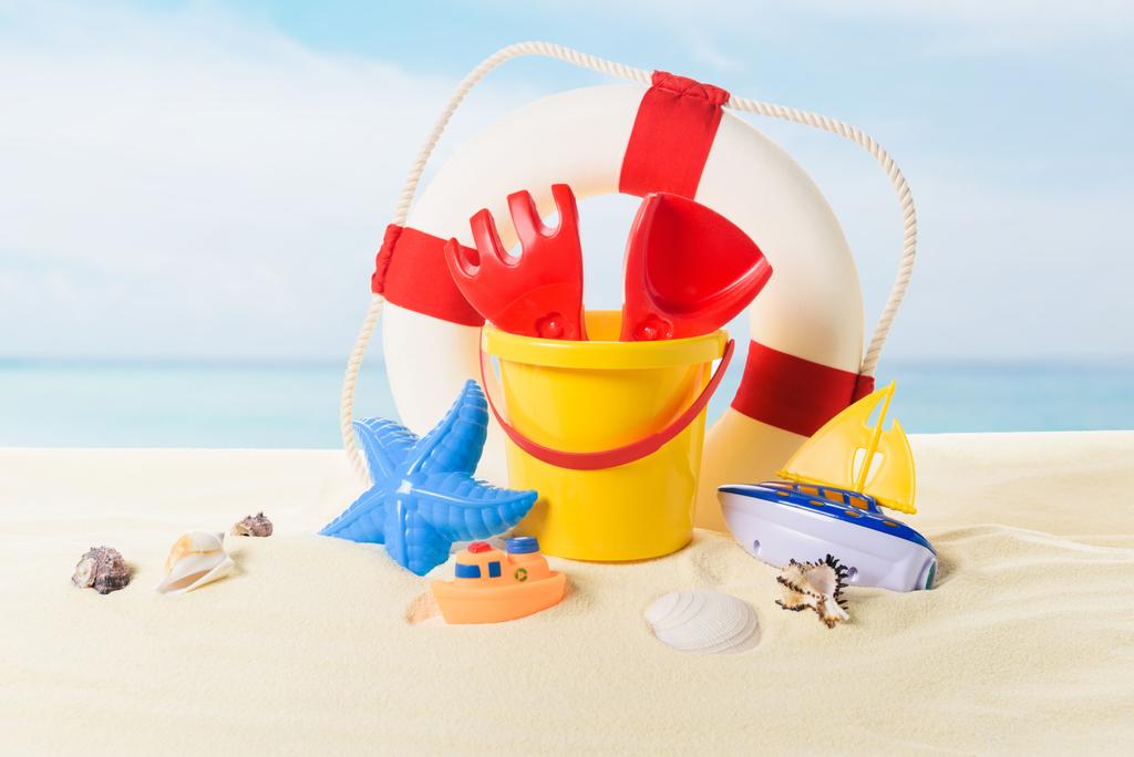 Leven ring en strand speelgoed in zand op blauwe hemelachtergrond - Foto, afbeelding
