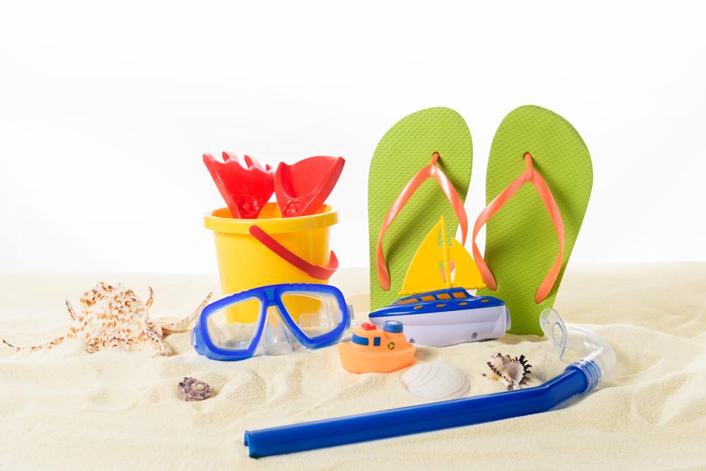 Strand speelgoed en flip-flops met duikbril in zand geïsoleerd op wit - Foto, afbeelding