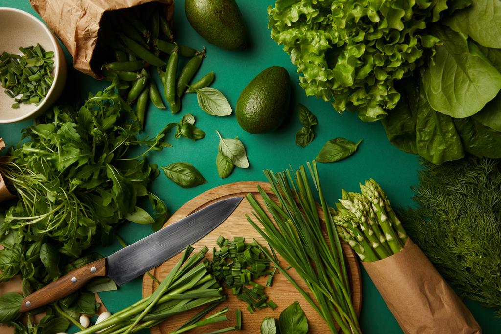 yeşil yüzeyi ahşap kesme tahtası ve bıçak ile çeşitli olgun sebze üstten görünüm - Fotoğraf, Görsel