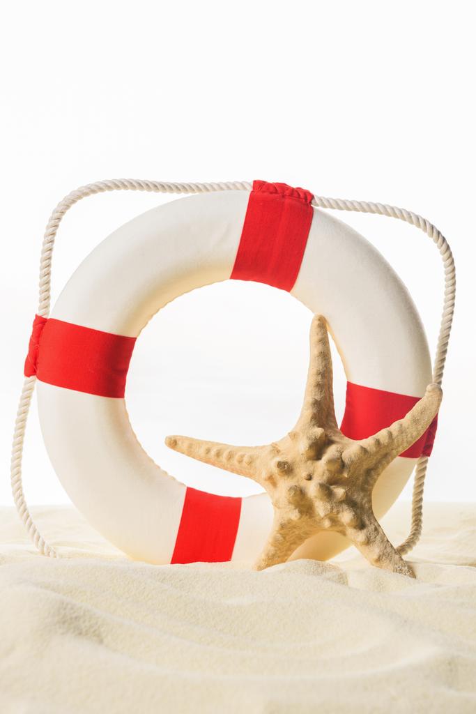 Кольцо жизни и морская звезда в песке изолированы на белом
 - Фото, изображение