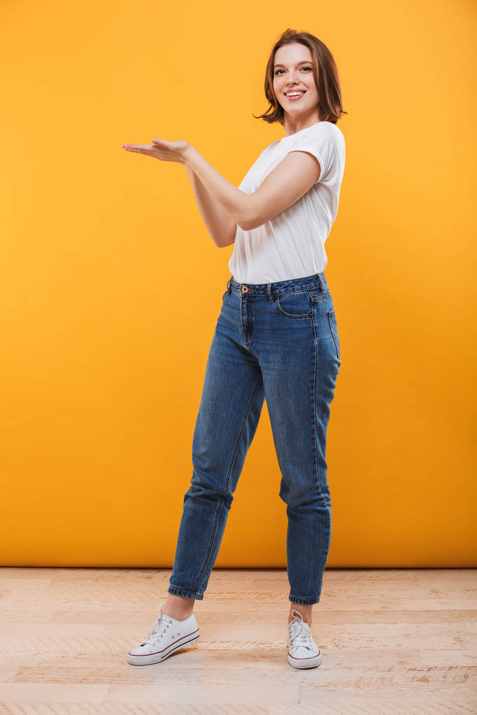 Image of cheerful young woman standing isolated over yellow background showing copyspace. - Photo, Image